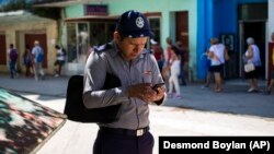 Un policía se conecta a Internet usando un teléfono celular en La Habana (AP/Desmond Boylan/Archivo)