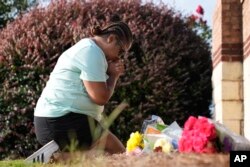 Linda Carter, de Grayson, Georgia, se arrodilla cerca de la Escuela Secundaria Apalachee para colocar flores por los estudiantes y profesores asesinados el jueves 5 de septiembre de 2024, en Winder, Georgia (AP Photo/Brynn Anderson).