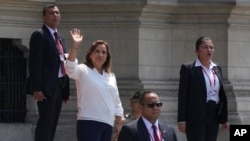 Rodeada de agentes de seguridad, la presidenta de Perú, Dina Boluarte, saluda a la prensa en el exterior del palacio presidencial, en Lima, Perú, el 10 de enero de 2023. (AP Foto/Martín Mejía)