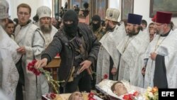 CRISIS EN SLAVIANSKUn guerrillero armado prorruso echa flores sobre los cuerpos de tres hombres durante el funeral celebrado en una iglesia ortodoxa de Slaviansk, Ucrania, el 22 de abril del 2014. 