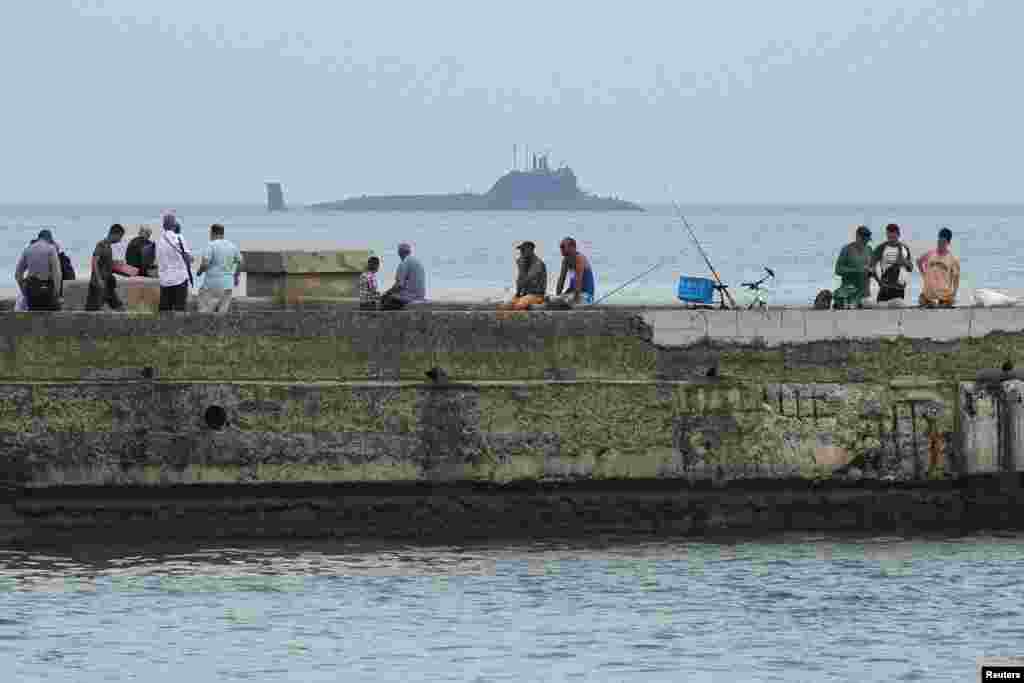 Los pescadores habituales del Malecón habanero continúan su rutina de siempre mientras observan la entrada del submarino ruso de misiles de crucero de propulsión nuclear Kazán en la bahía de La Habana, Cuba, 12 de junio de 2024. REUTERS/Alexandre Meneghini