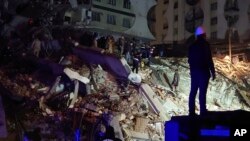 Gente trata de llegar hasta residentes atrapados en un edificio derruido en Diyarbakir, en el sureste de Turquía. (AP Foto/Mahmut Bozarsan)